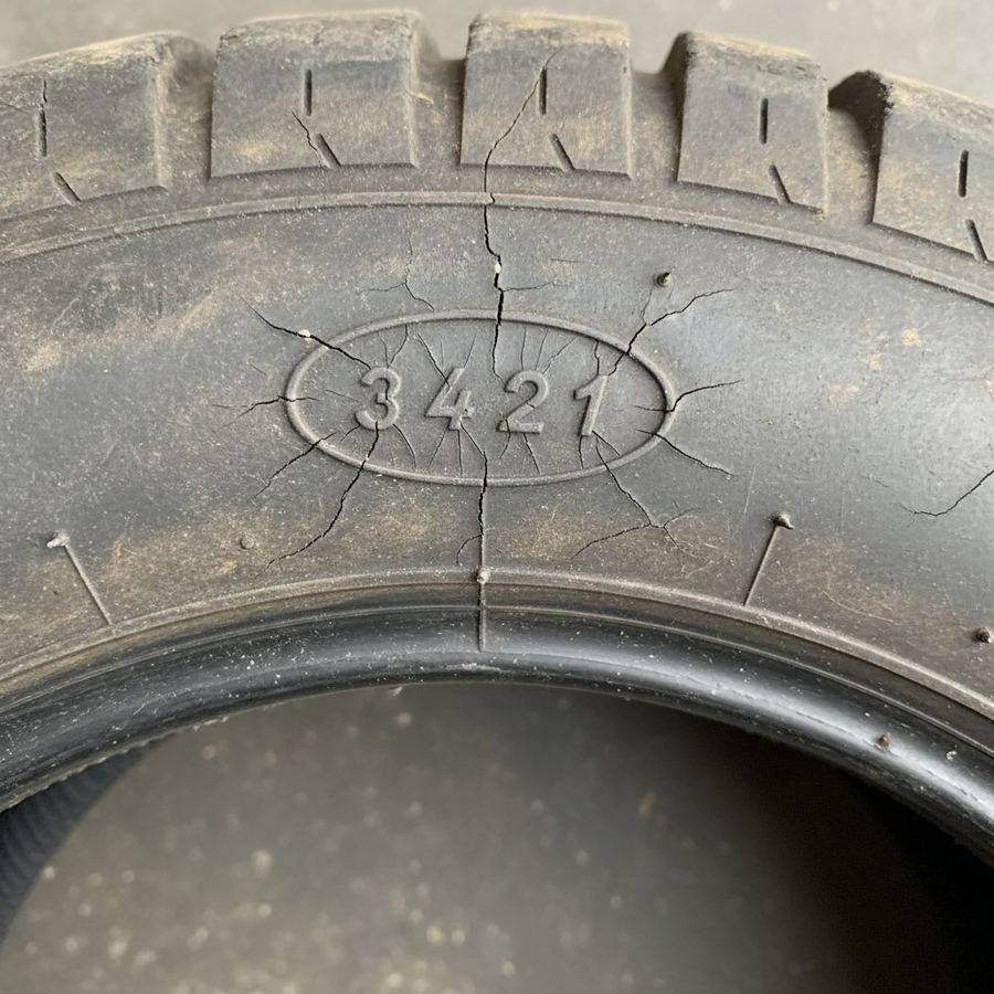 Close-up of a tire sidewall showing DOT date code and visible cracking